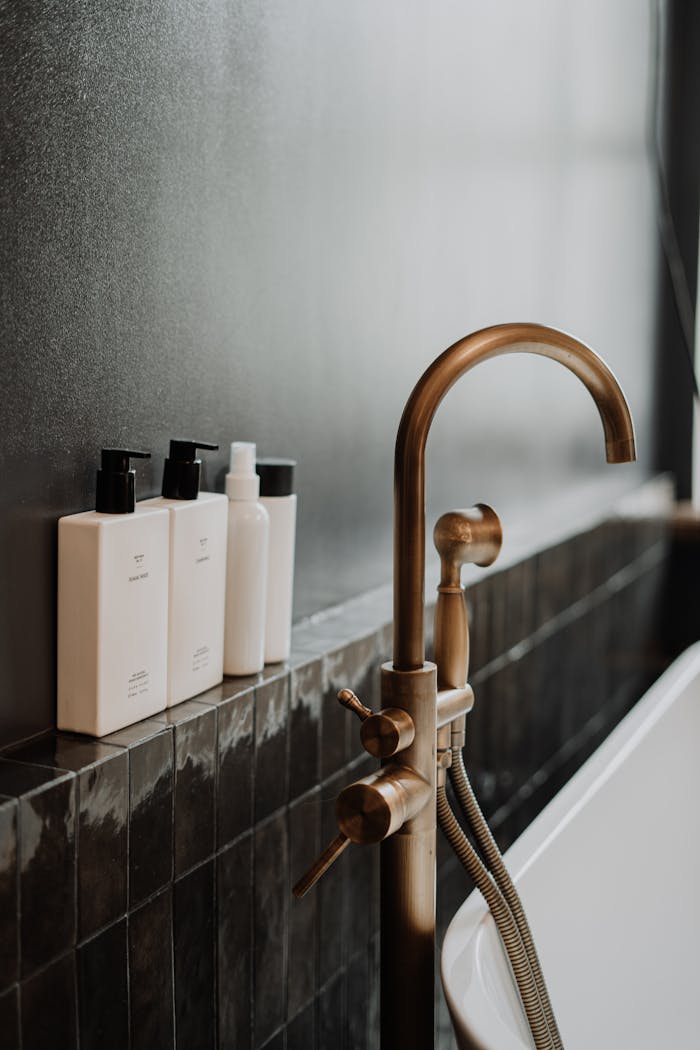 Sleek modern bathroom featuring a golden water tap and minimalist bottles.
